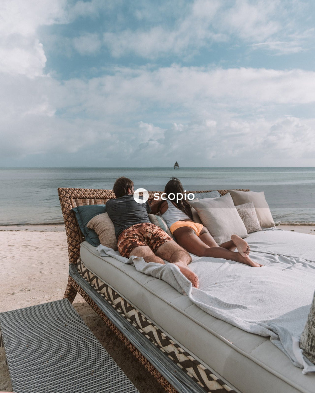 Couple lying on white bed near sea