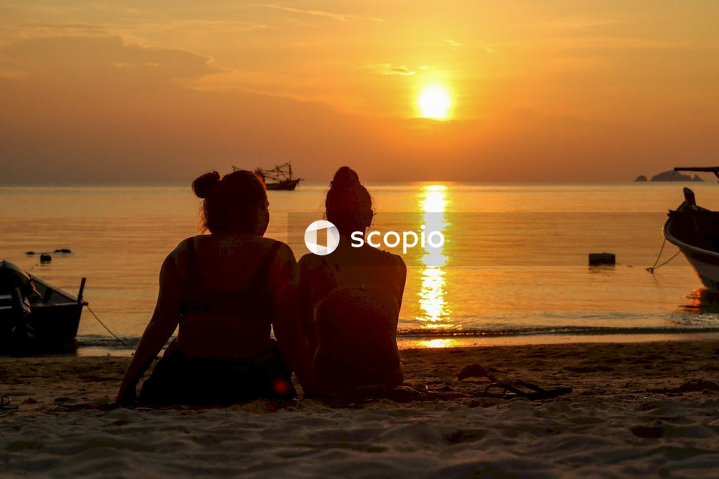 Couple sitting on beach during sunset