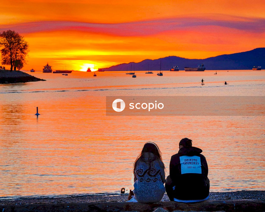 Couple sitting on beach during sunset