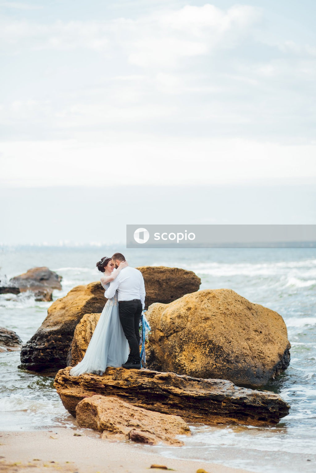 Couple sitting on brown rock near body of water
