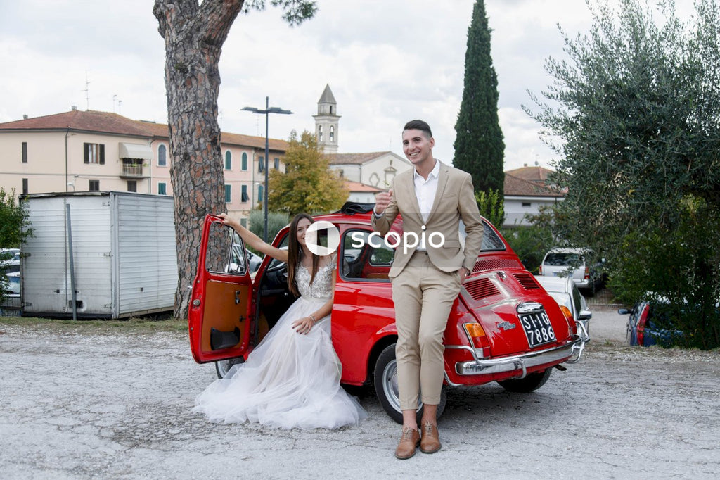 Young married couple doing a photoshoot near small red car