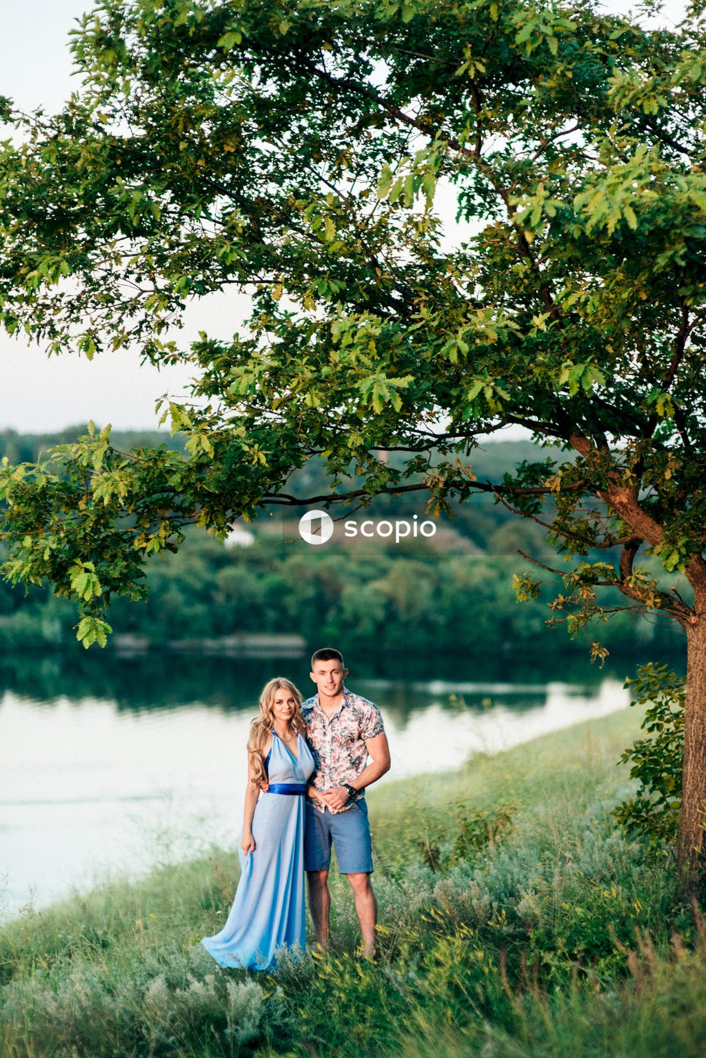 Couple standing beside tree near lake