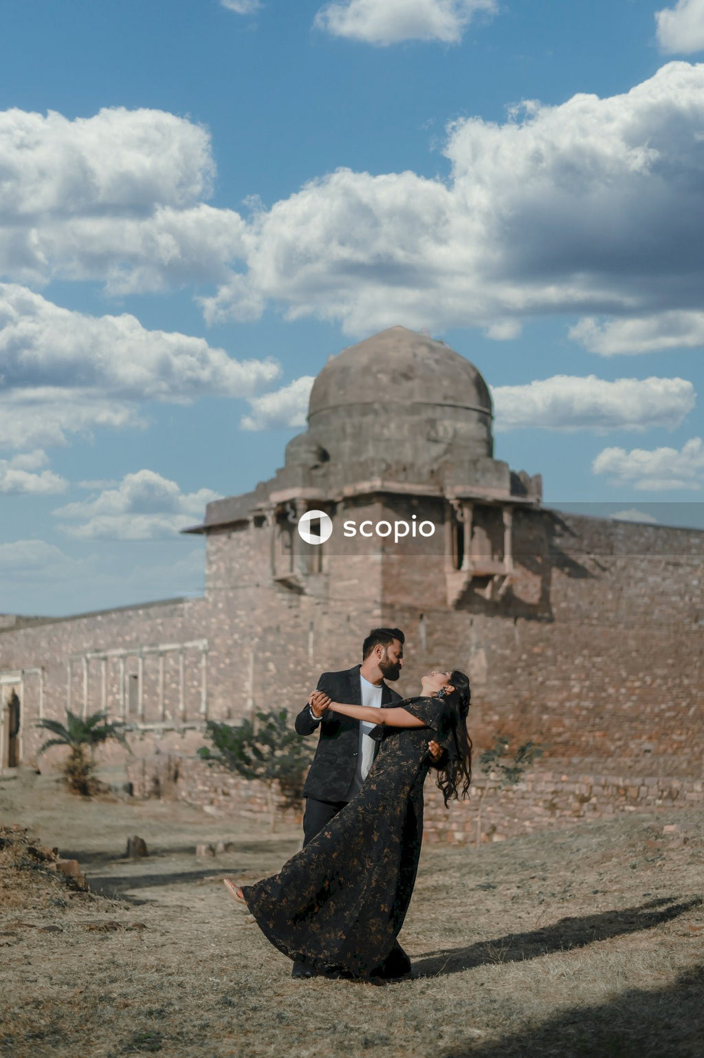 Couple standing near pyramid under blue sky