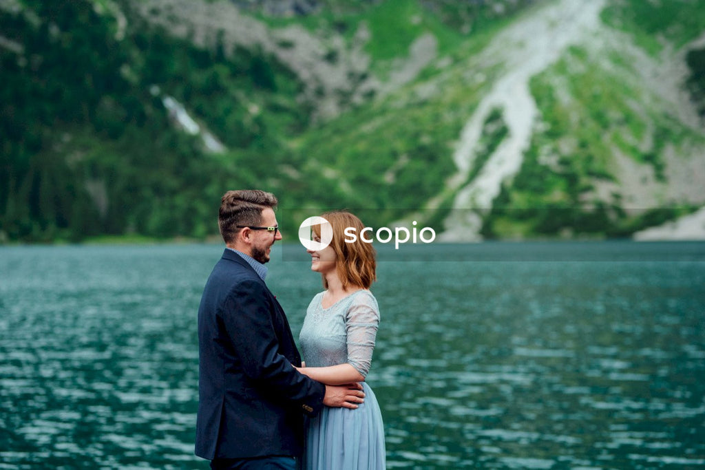 Couple standing on a cliff by a lake