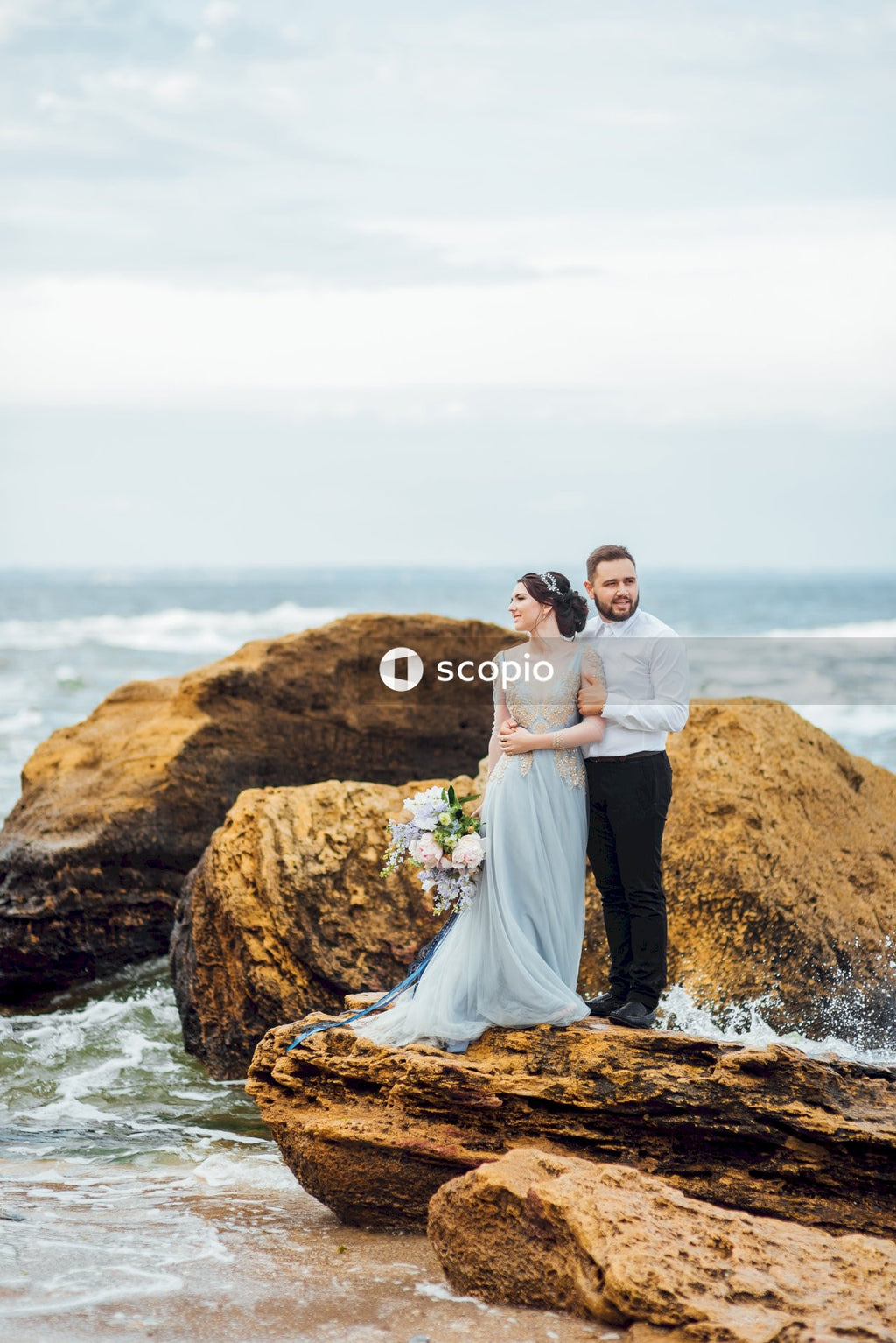 Couple standing on brown rock near body of water