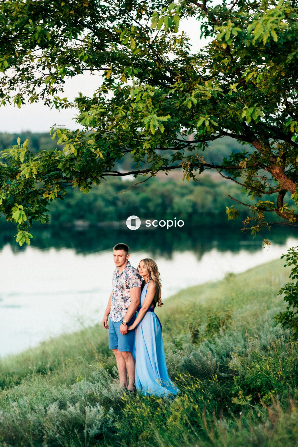 Couple standing on green grass near lake