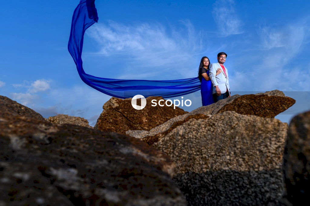 Couple standing on rock under blue sky