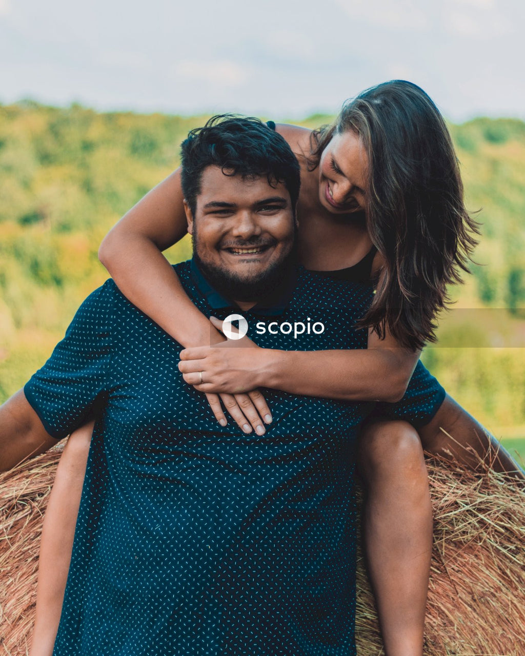 Man in blue and white polka dot shirt hugging woman in blue dress