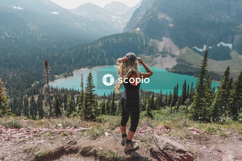 Woman in black tank top and black pants standing on brown rocky mountain