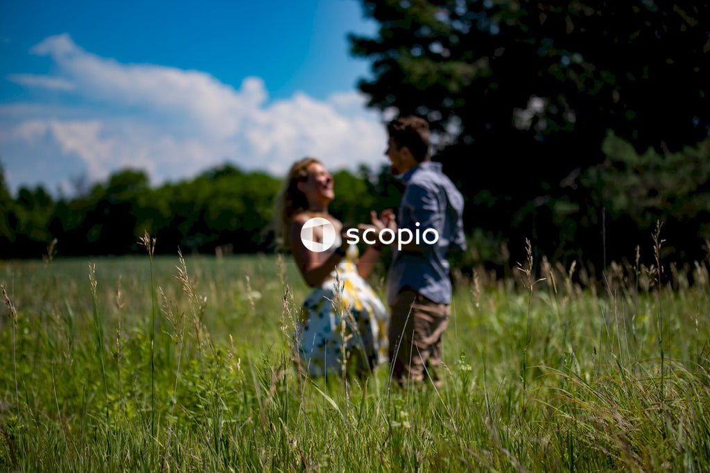 Man and woman holding hands while walking on green grass field