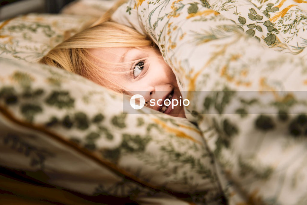 Blond child peeking over a blanket