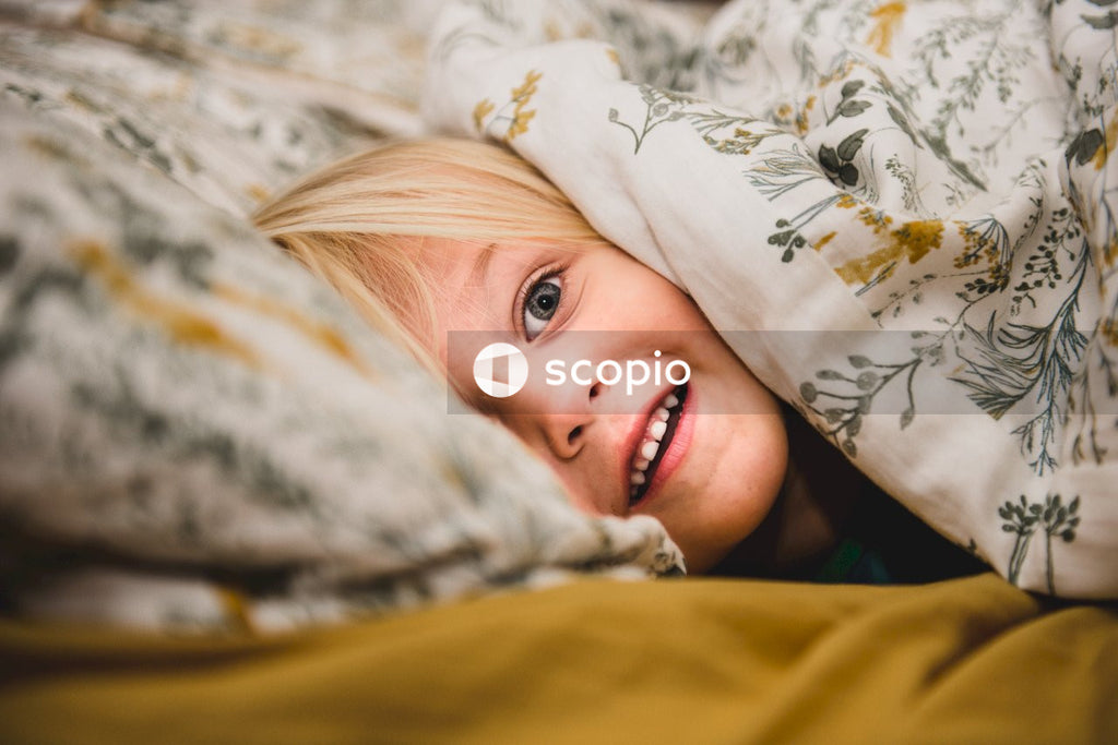 Woman lying on bed covered with blanket
