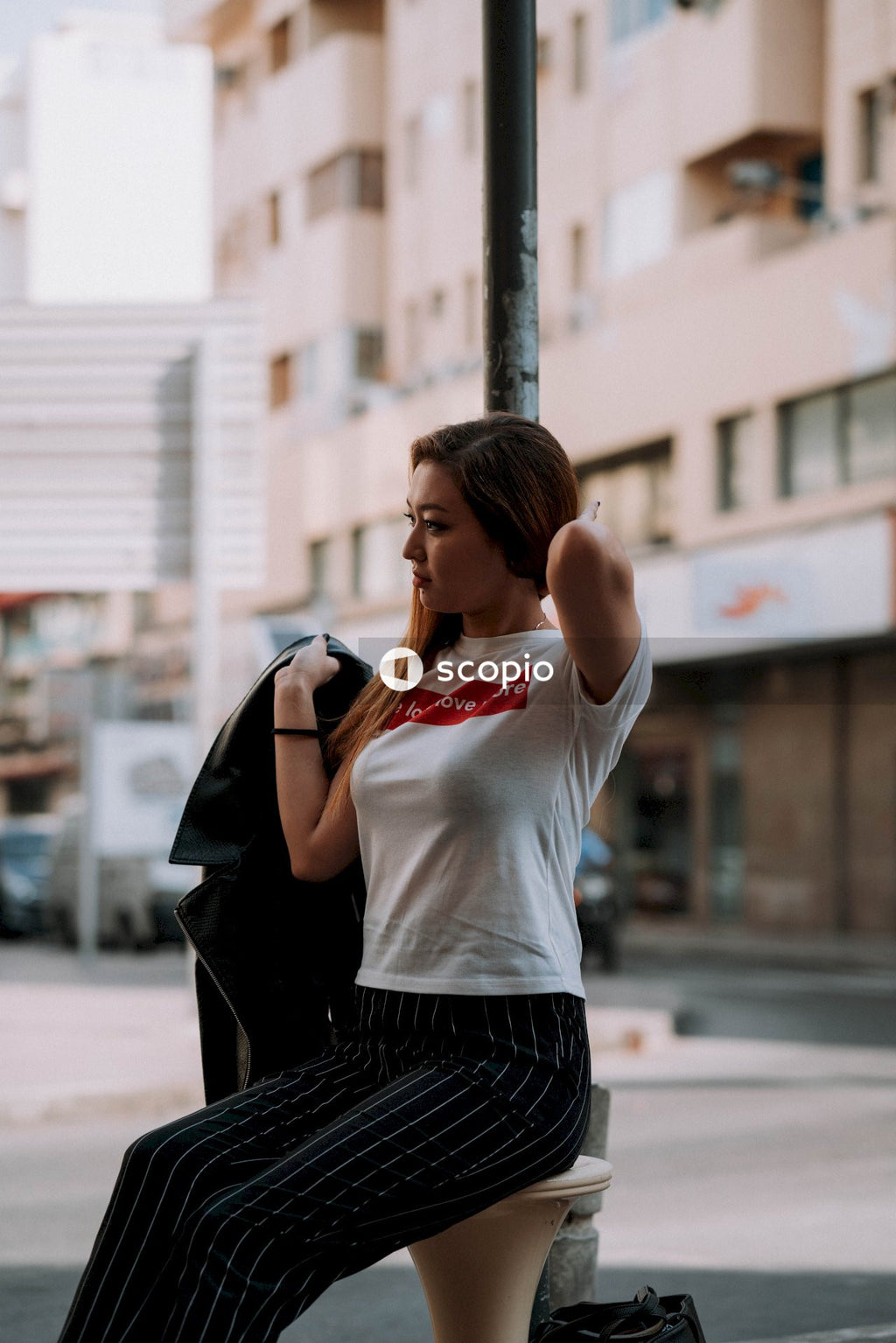 Woman sitting on stool while holding coat on her right hand