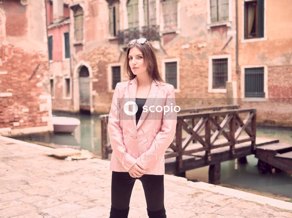 Woman in pink blazer and black pants standing on brown concrete floor