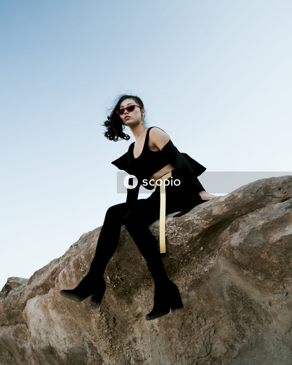 Woman in dark outfit posing on rock