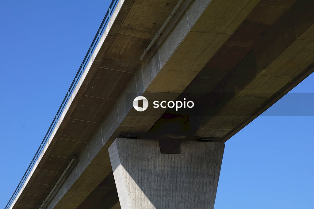 Low angle photography of gray concrete bridge under blue sky
