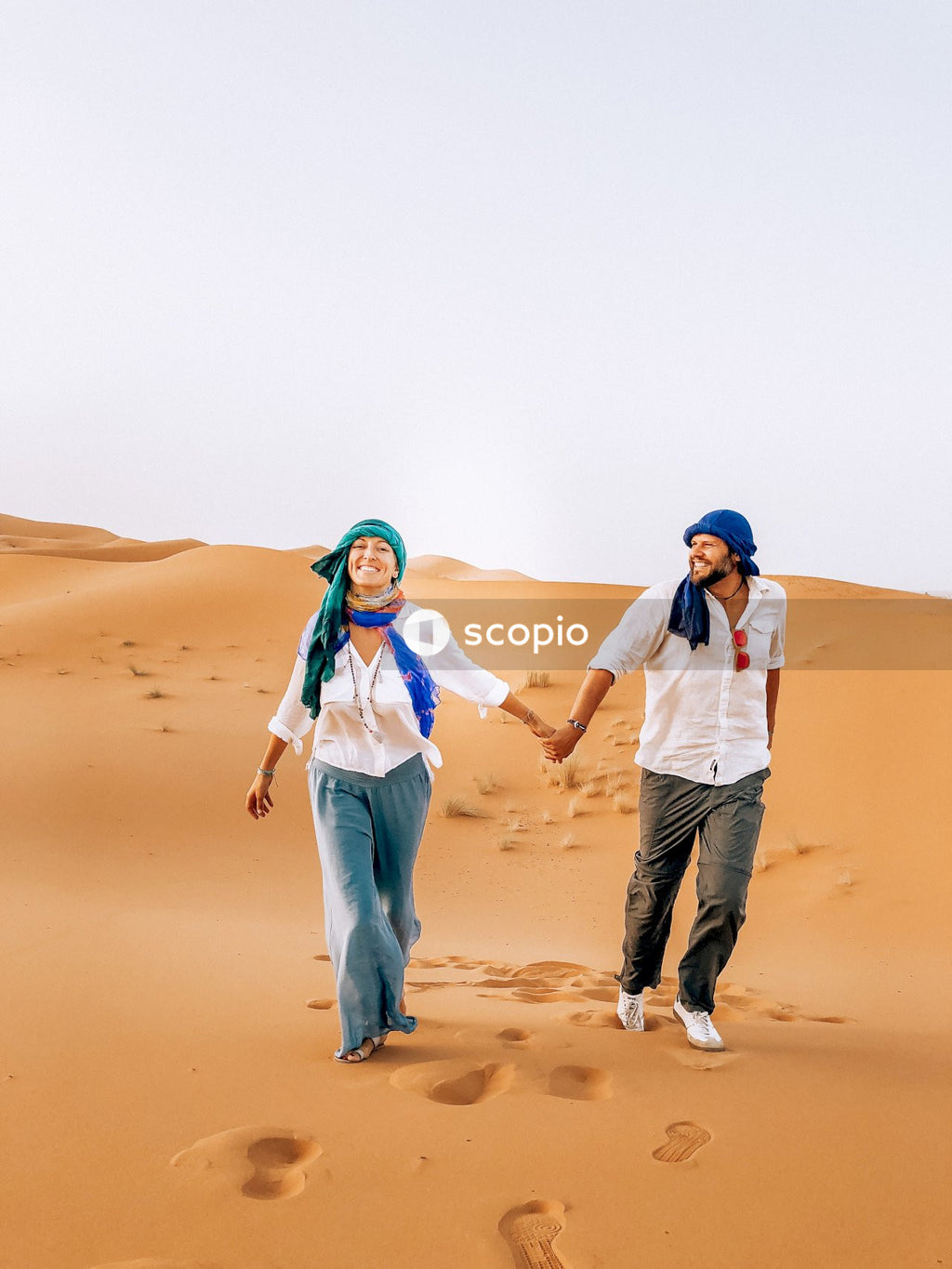 Man and woman holding hands and walking at the desert