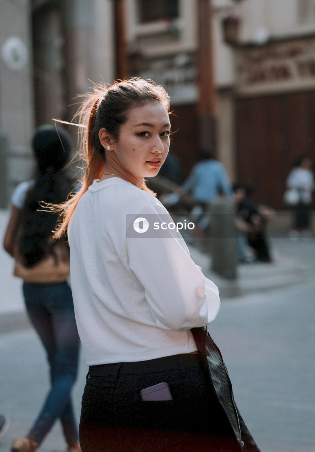 Woman in white long sleeve shirt and black skirt standing on sidewalk