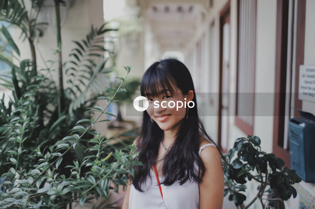 Woman with bangs posing near flowers and bushes