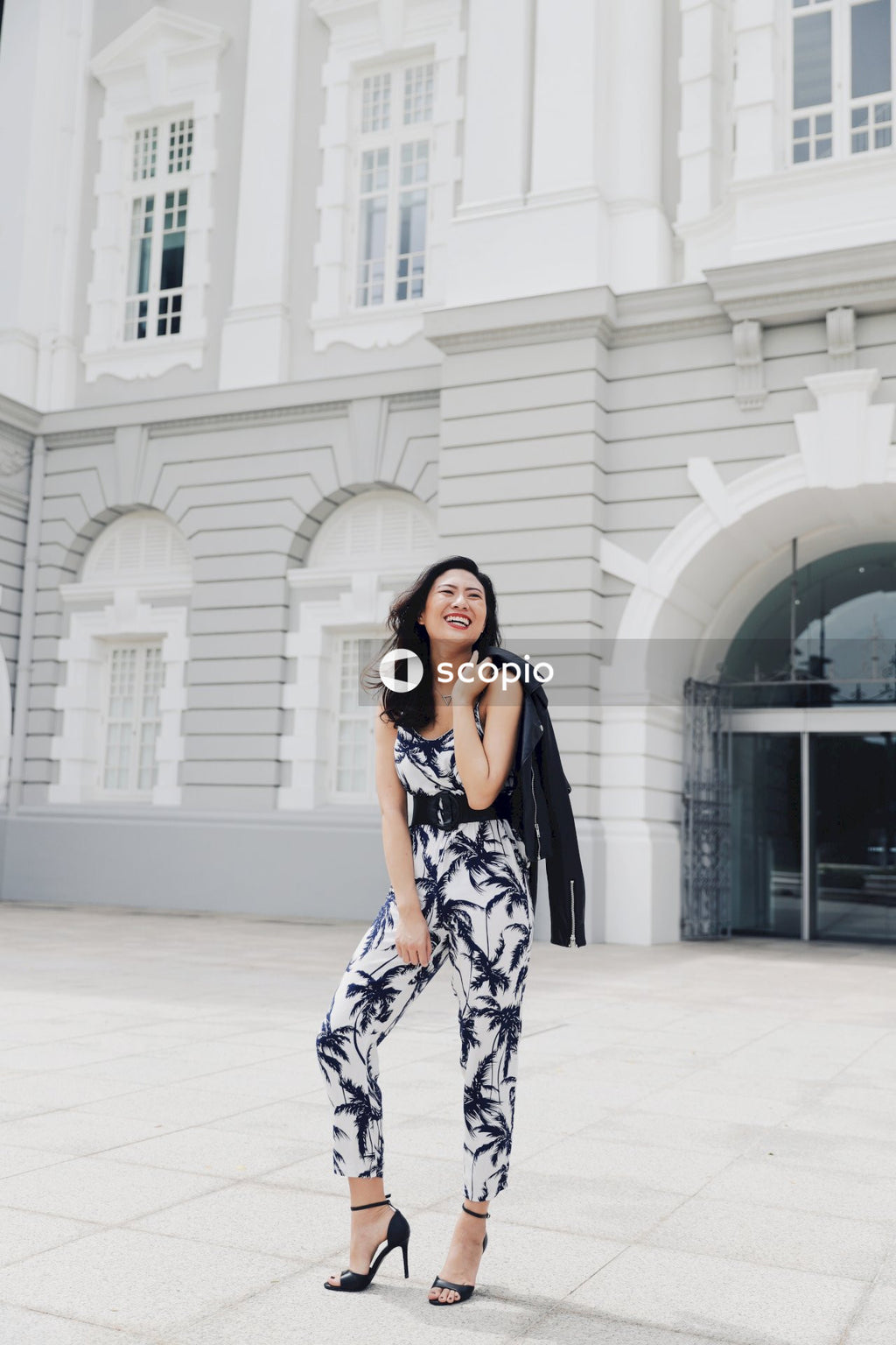 Woman in light and dark jumpsuit posing in front of building