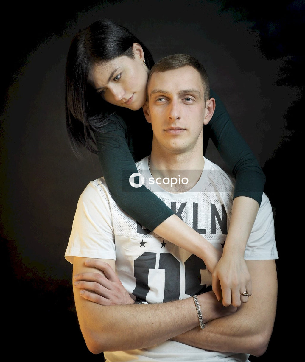 Man in black long sleeve shirt hugging woman in white t-shirt