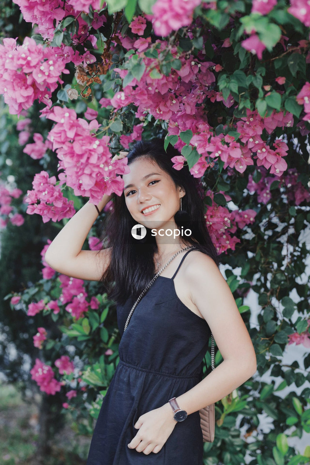 Woman in dark dress posing near flowers bushes