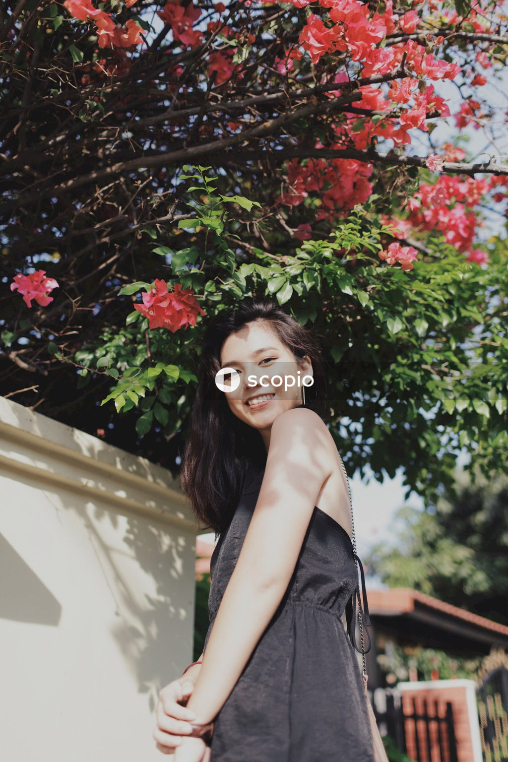 Woman in dark dress posing near flowers bushes