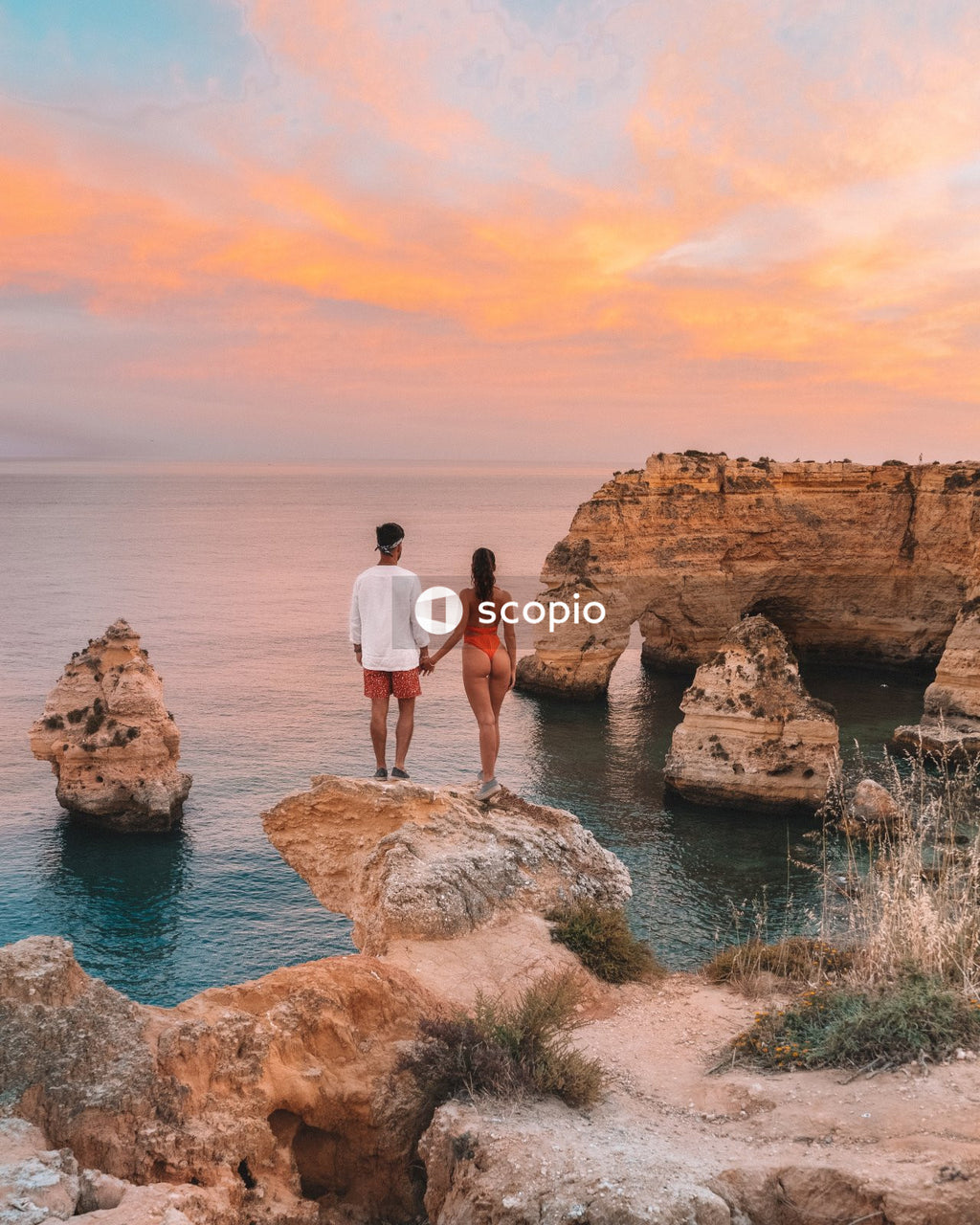 Couple standing on rock formation near body of water