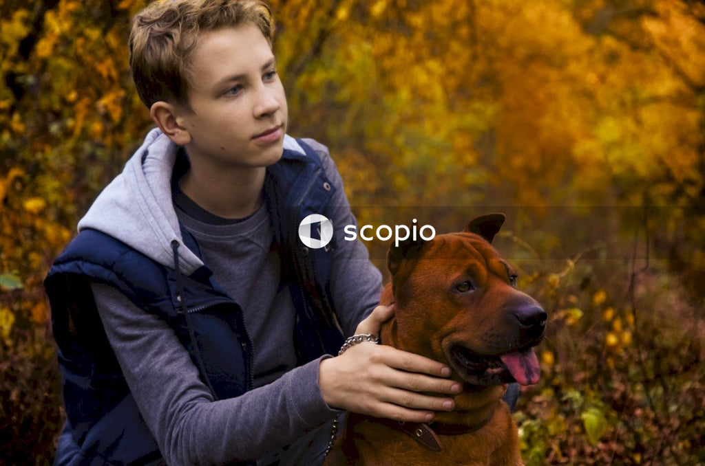 Boy in black leather jacket hugging brown short coated dog