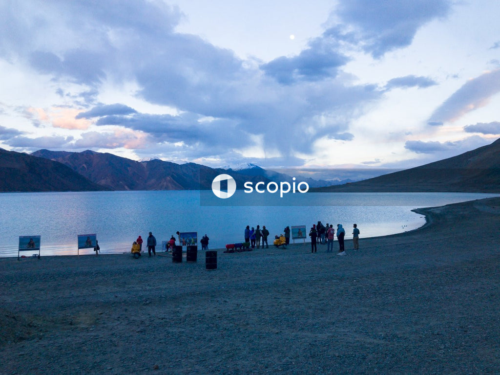 People standing on gray sand near body of water
