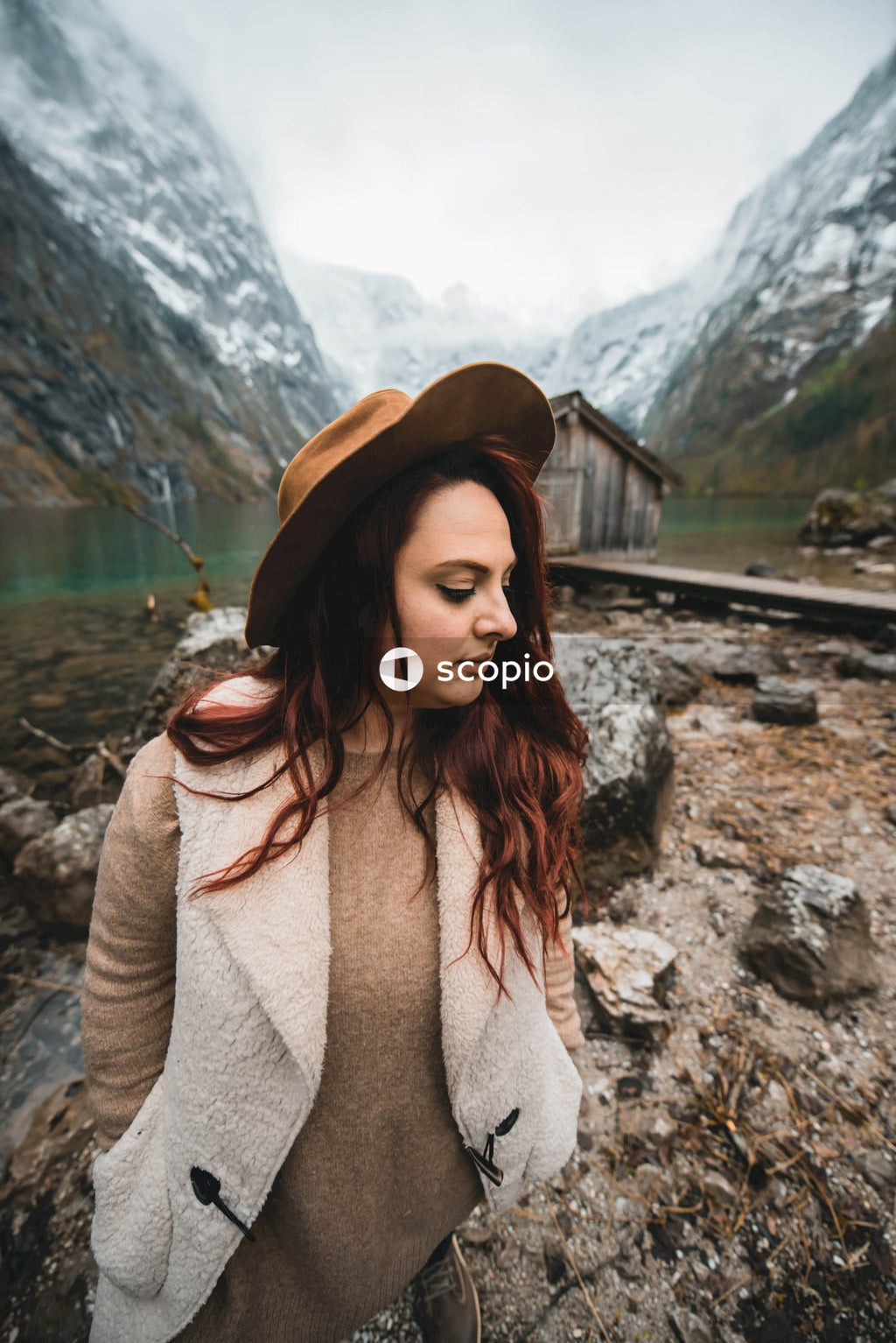 Mature woman in brown hat standing against natural landscape