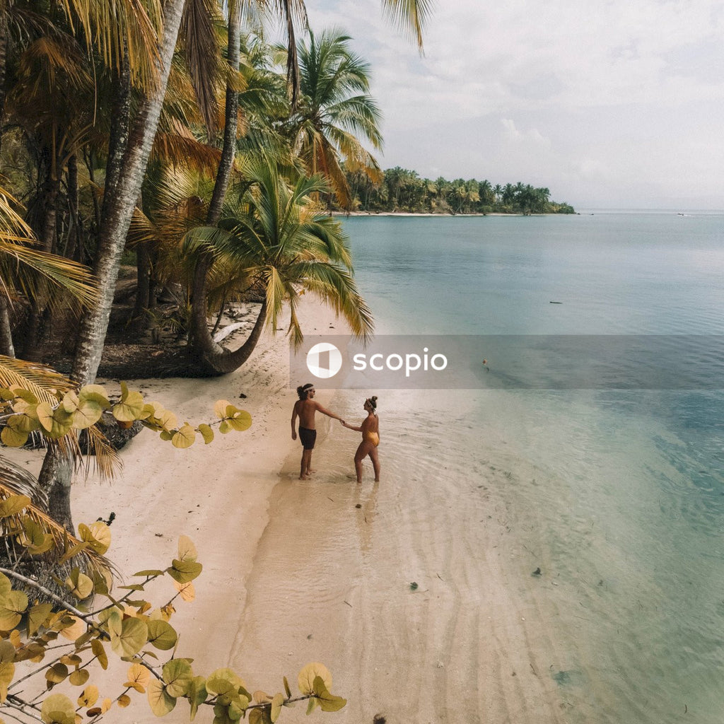 Man and woman in bathing suit holding hands at the beach
