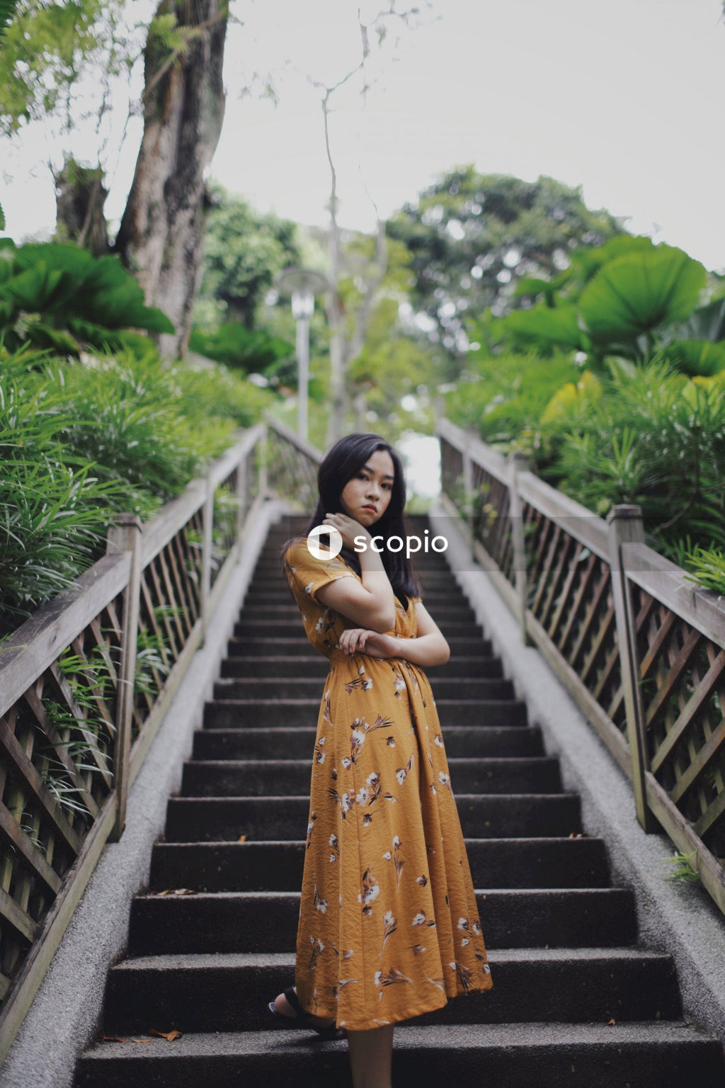Asian woman in orange dress standing on stairs