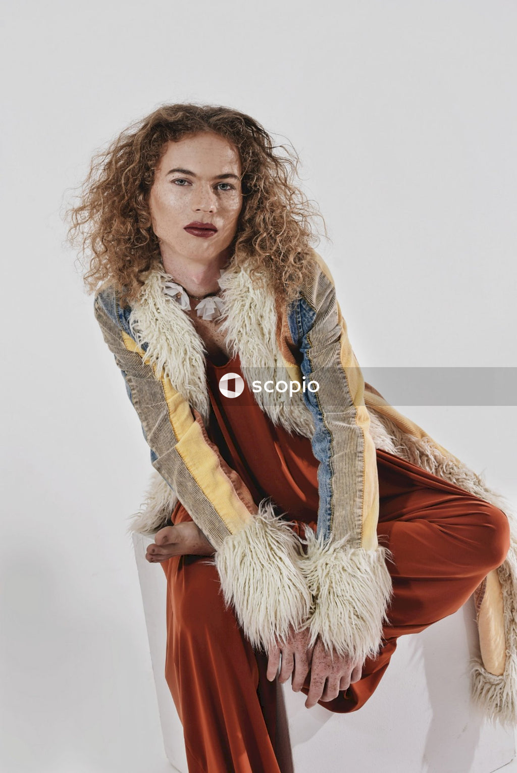 Portrait of trans woman wearing fur and make-up against light background