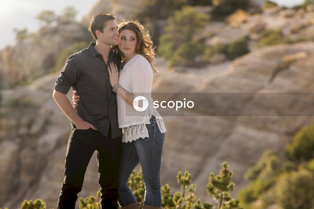 Smiling man and woman hugging each other and standing in green field
