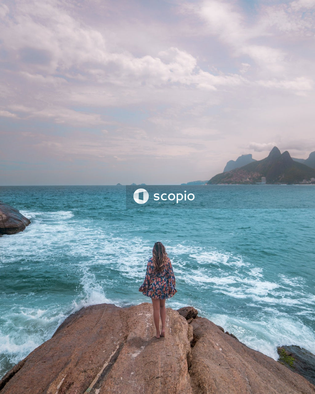Back view of woman standing on a rocky seashore