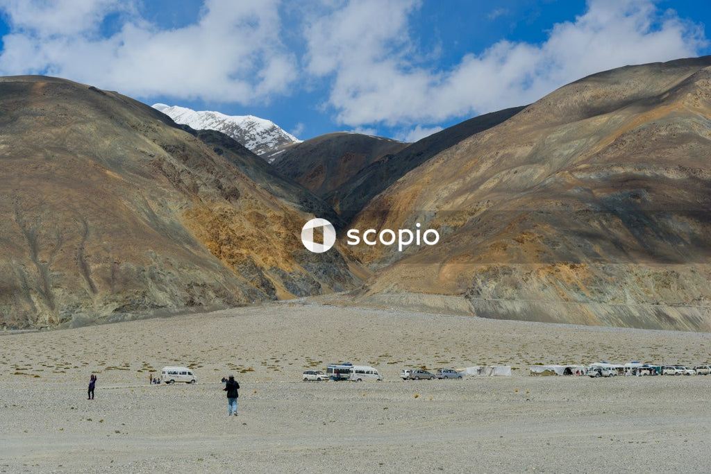 People walking on white sand near brown mountain under blue sky