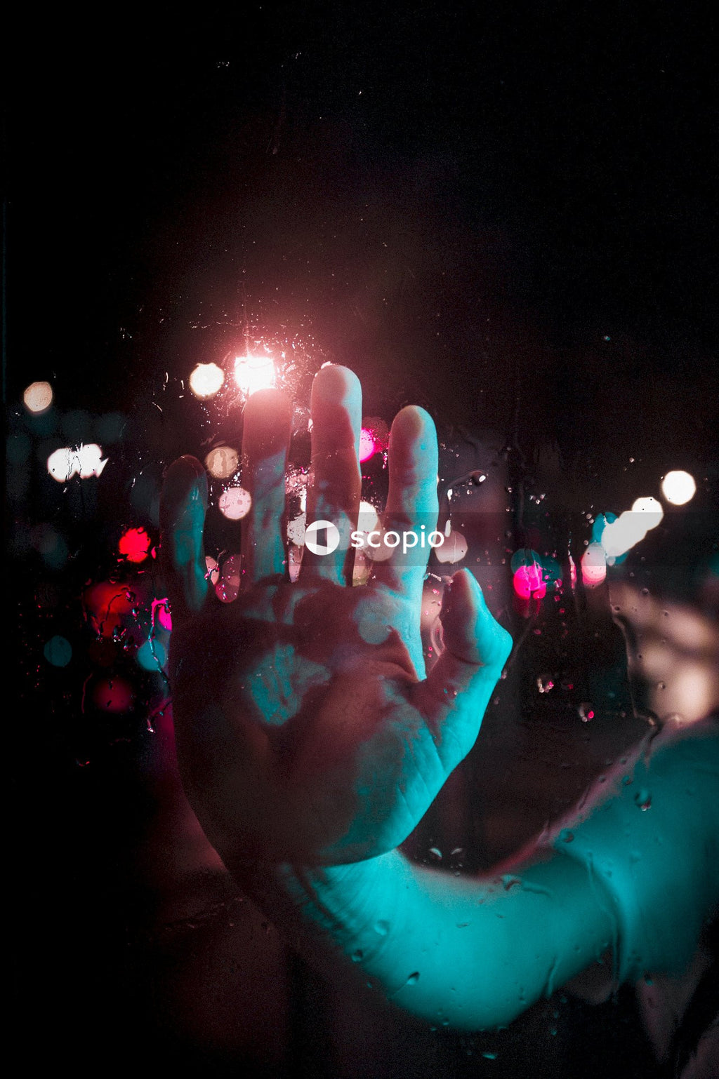 Shallow focus photo of person's hand with street lights in the background