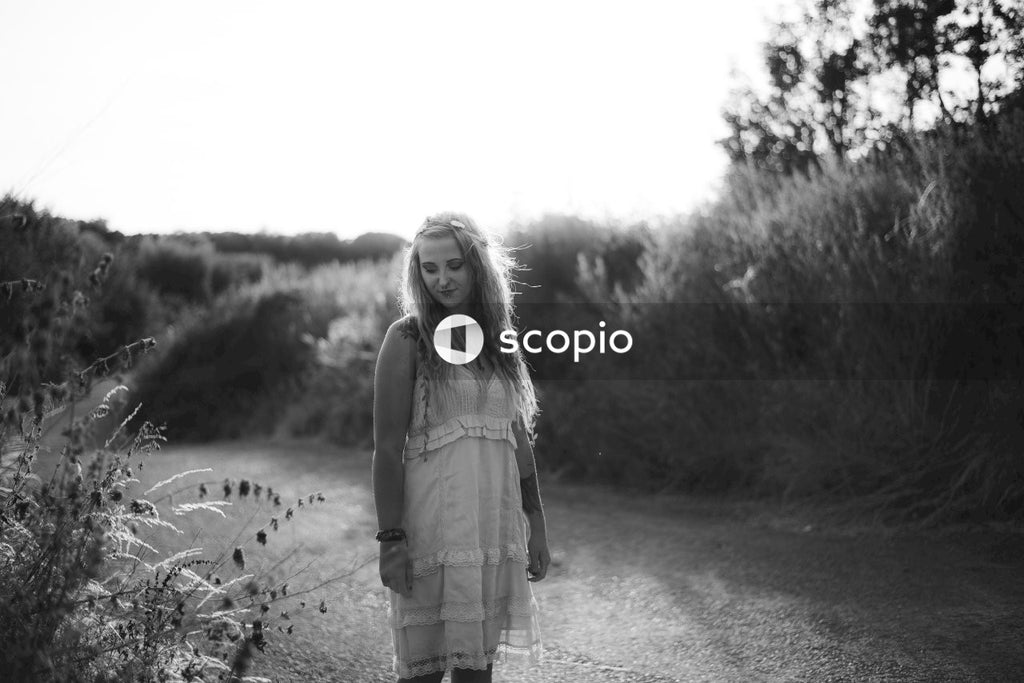 Grayscale photo of woman in tank top standing on road