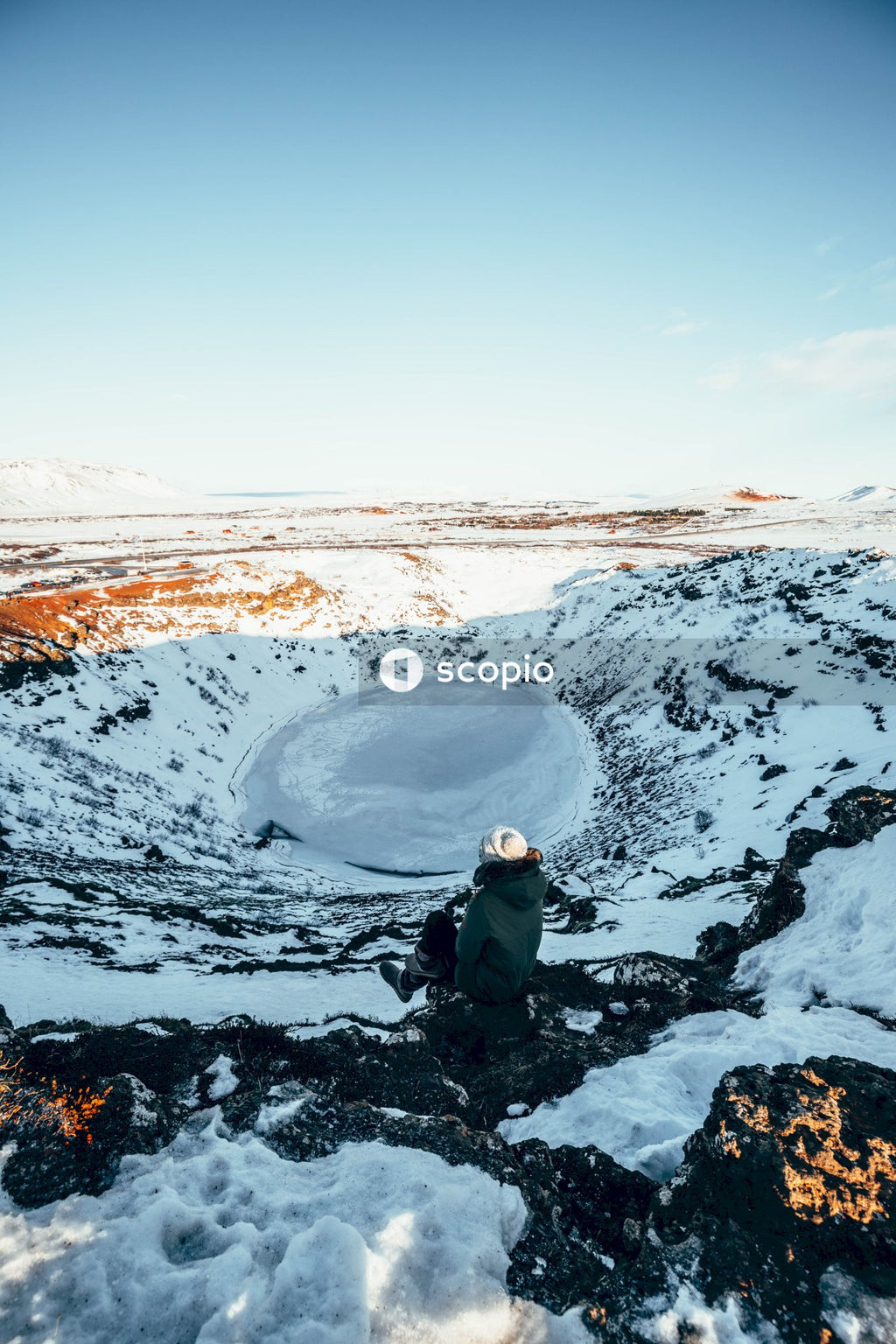 Person in black jacket and gray backpack standing on snow covered ground