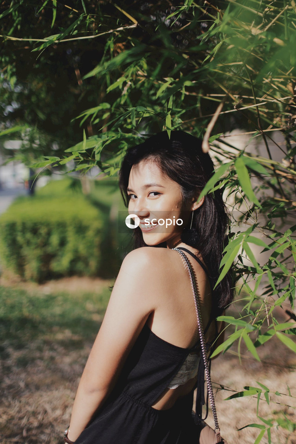 Woman in dark dress posing near flowers bushes