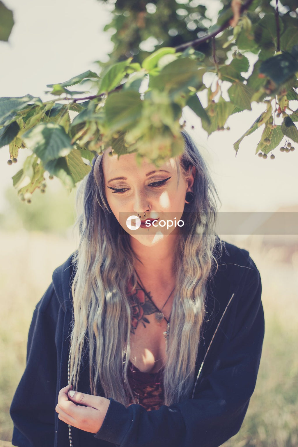 Woman wearing dark eyeliner standing beside tree