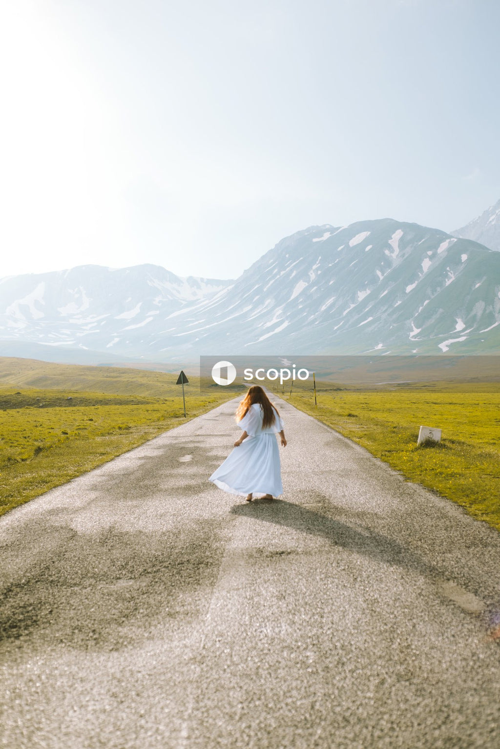 Woman in white dress walking on gray asphalt road