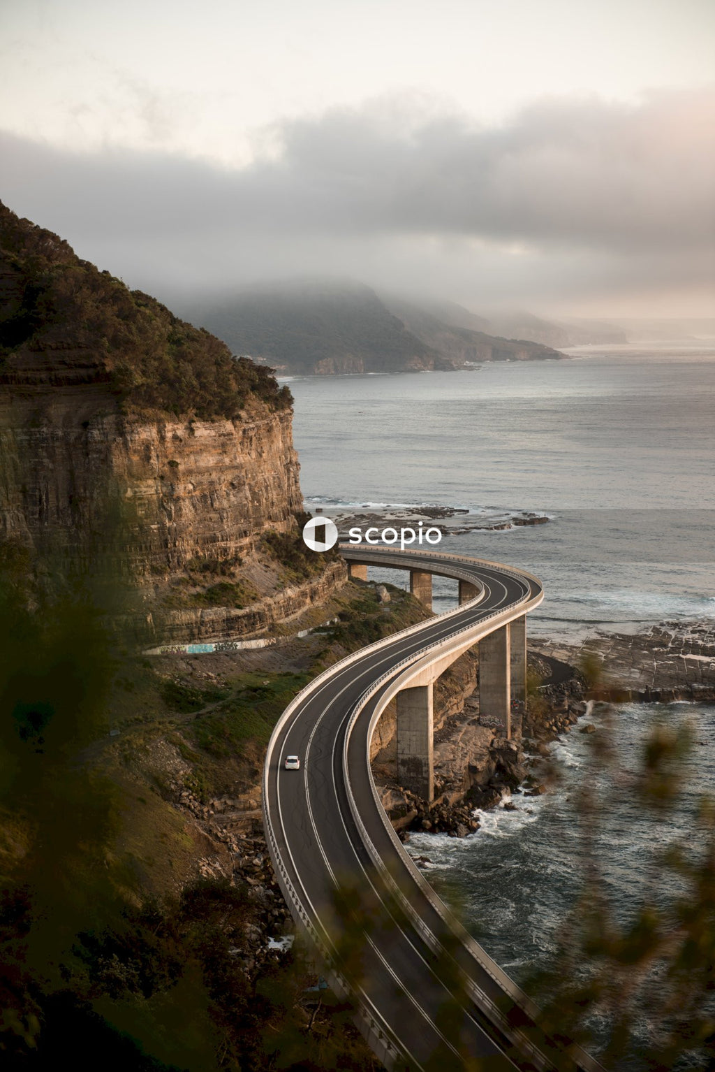 Gray concrete road near cliff and body of water