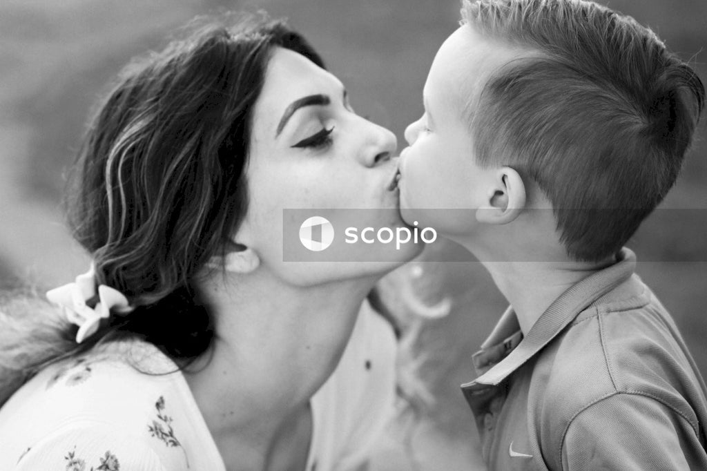 Grayscale photo of woman kissing boys cheek