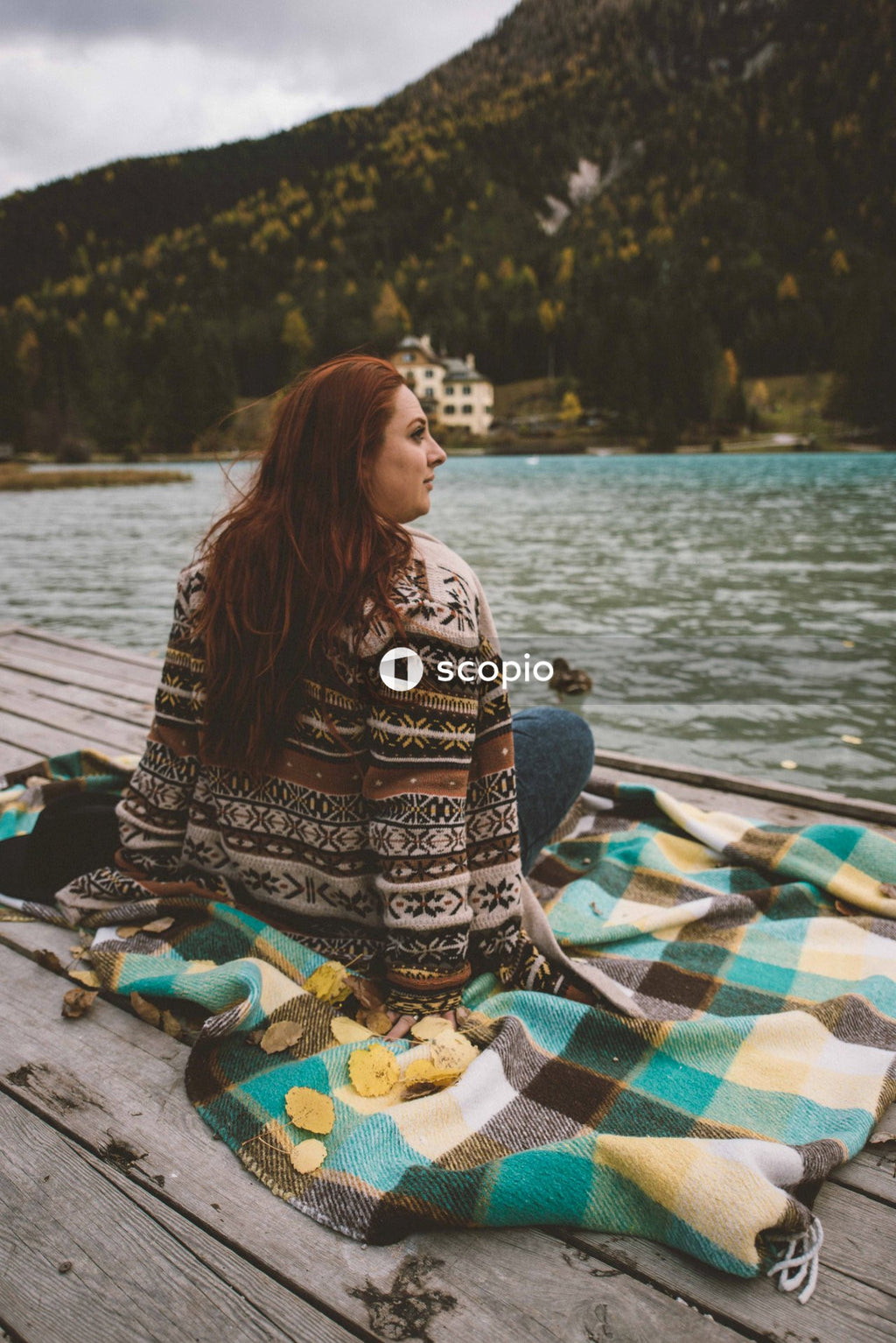 Back view of mature woman sitting on textile by the lake