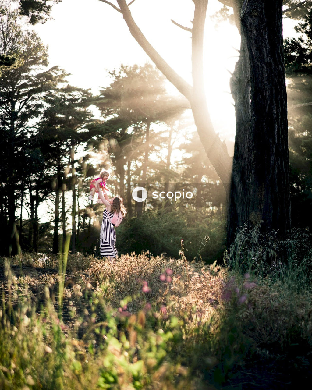 Woman lifting her girl child in the air in the forest in daylight