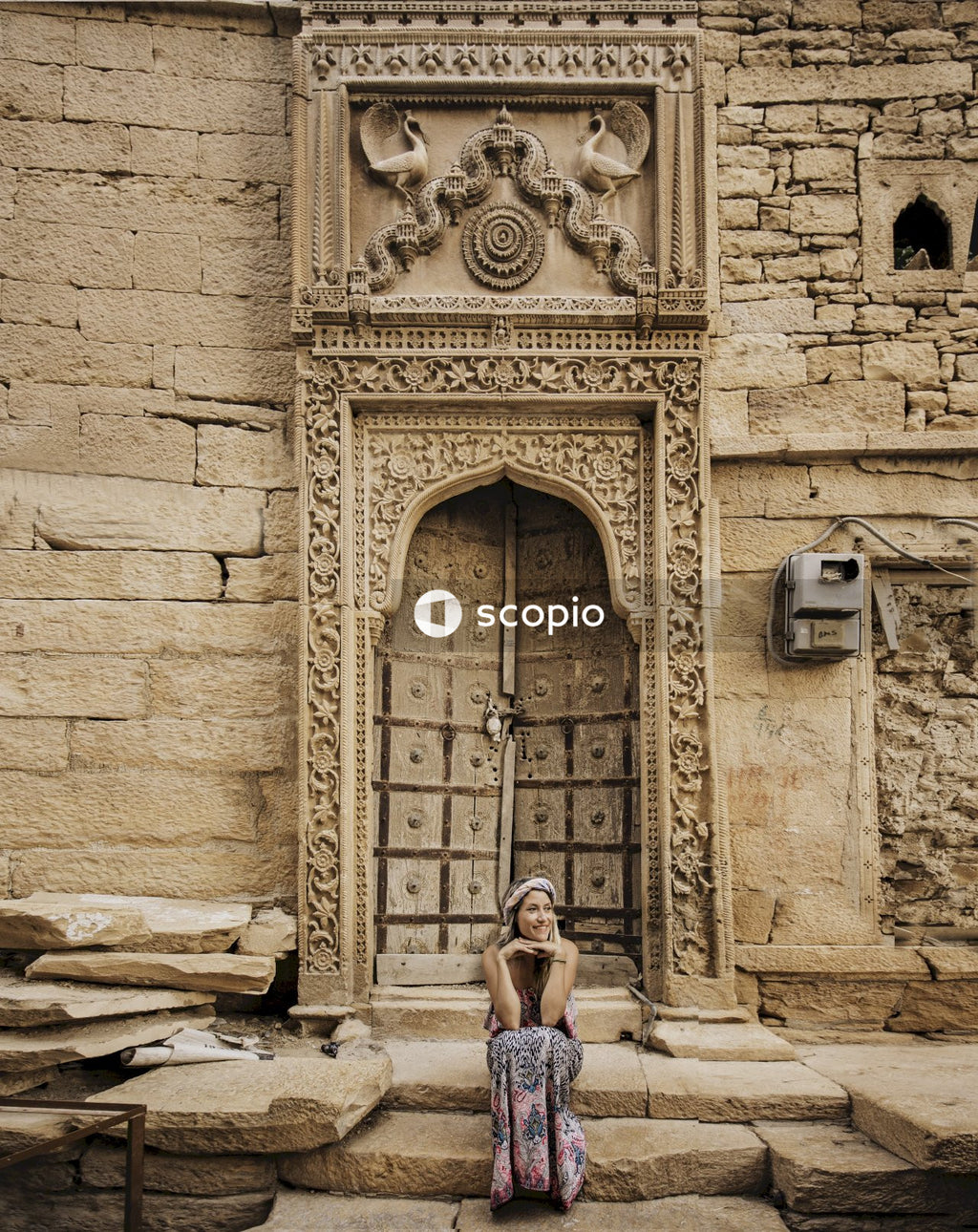 Woman sitting on doorstep of old brown ethnic building