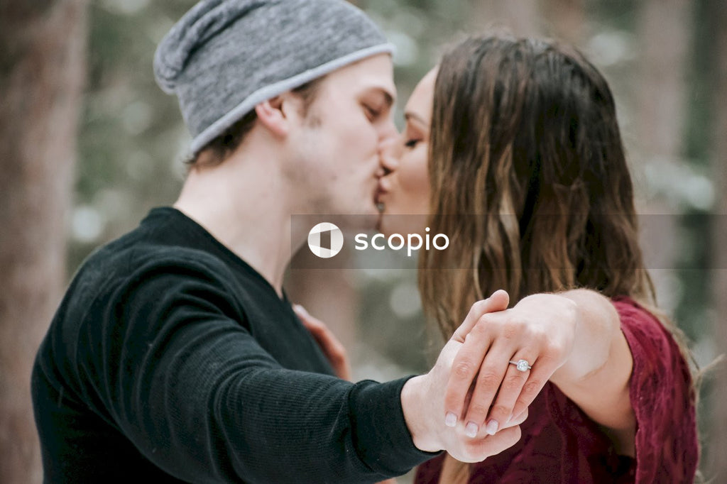 Man in black sweater kissing woman in red shirt