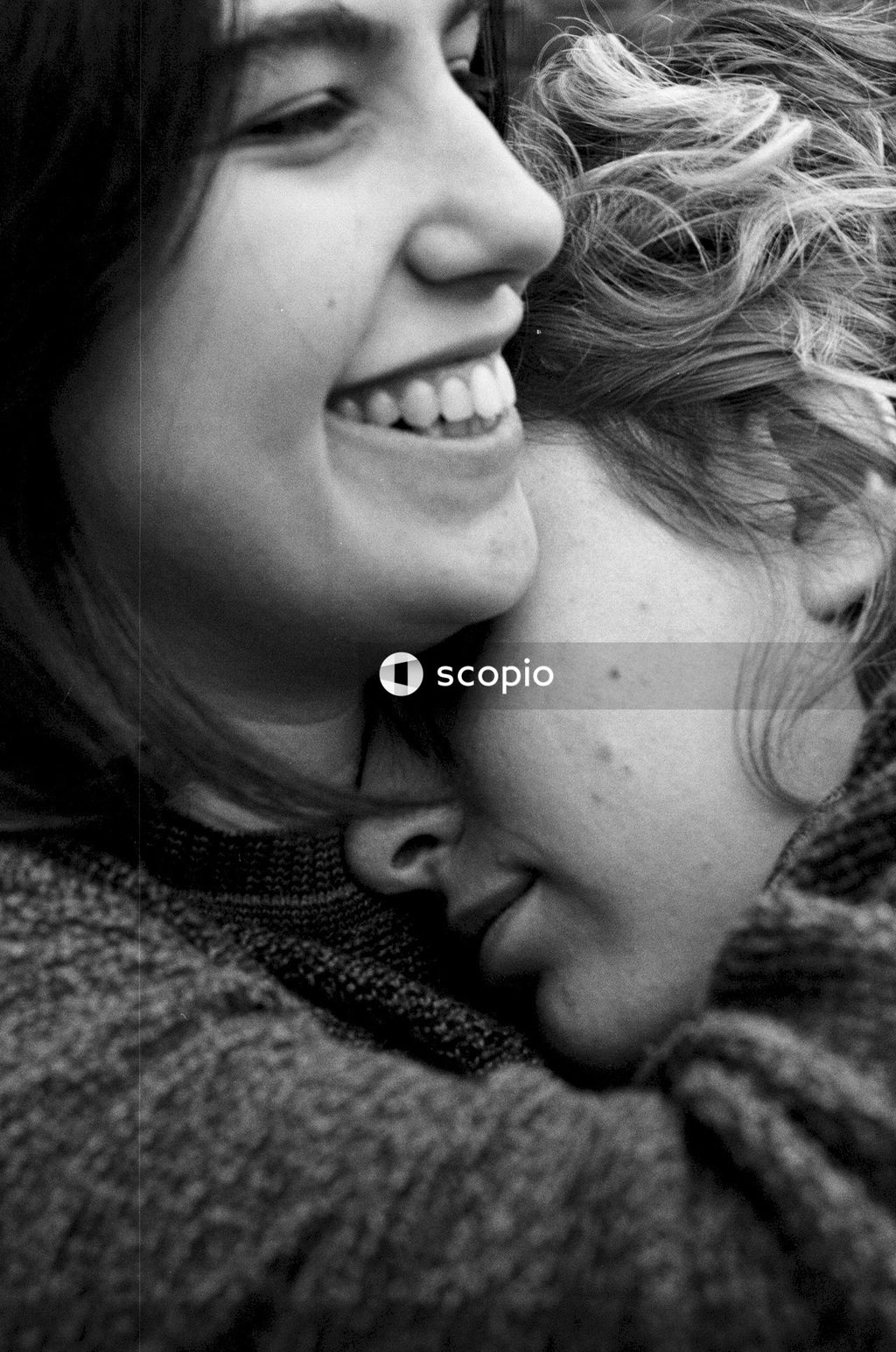 Close-up grayscale of two women hugging
